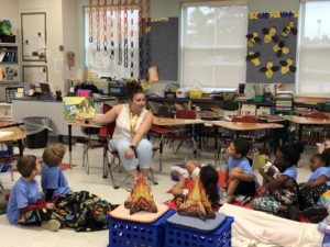 a guest reader reading to children in a camp-themed classroom