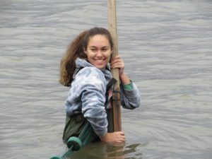 student wading in river and holding seine net