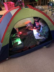 elementary students read together in a tent in the classroom