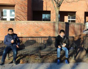 two elementary boys sit next to each other on an outdoor bench behind the school