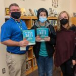 junior high school librarian Mr. Millar, 7th grade student Sean Delaney, and retired teacher Maryann Murphy holding the teacher text Sean and Maryann had poems published in