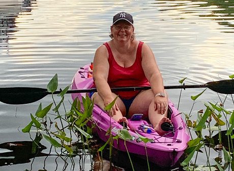 Stacy Silcock wearing a Yankees cap and sitting in a pink kayak