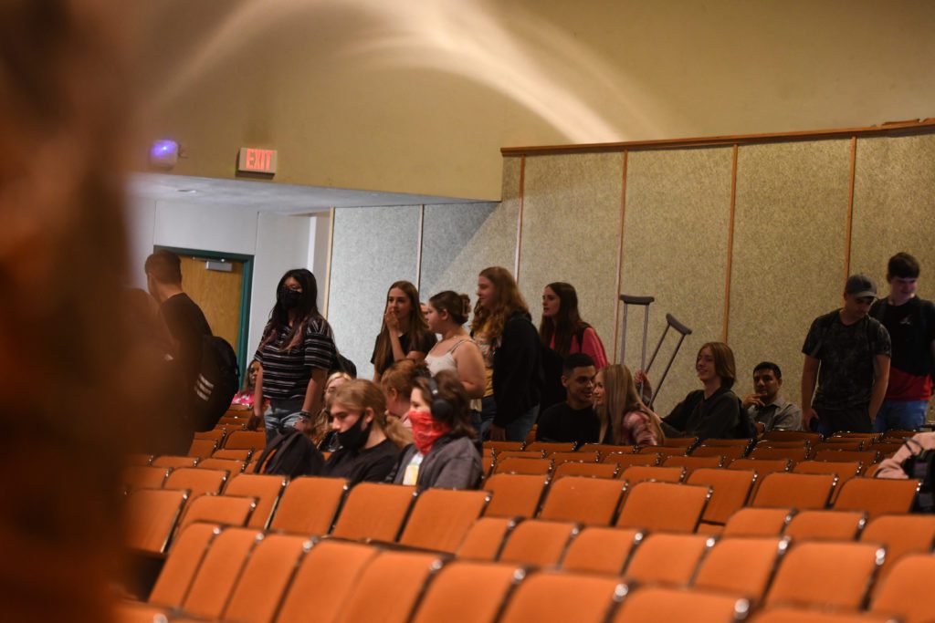 high school juniors seated and standing in auditorium